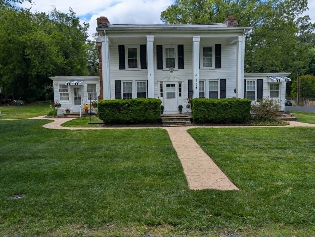 Colonial home with manicured lawn and trimmed foundation hedges