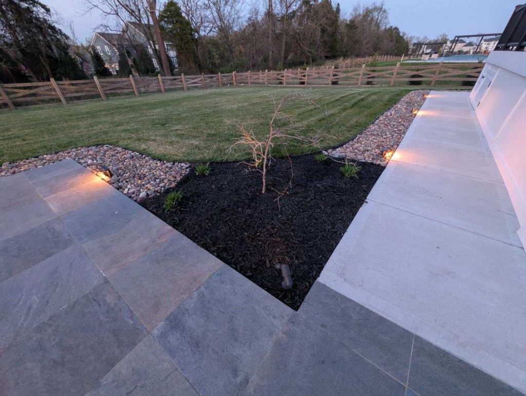 Curved mulch bed with ornamental grasses and stone wall