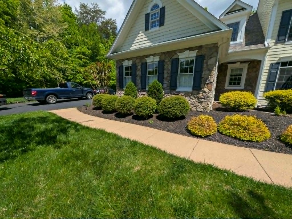 Stone-front home with mulched shrubs and curved walkway borders